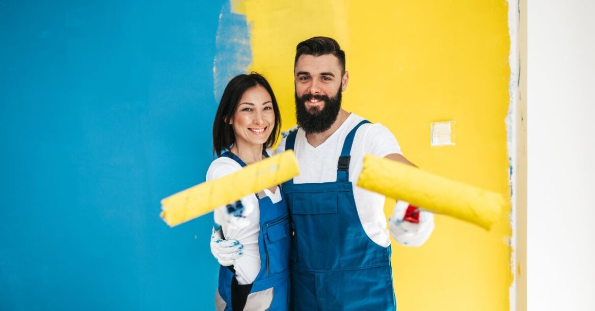 A couple painting a wall in two different colors.