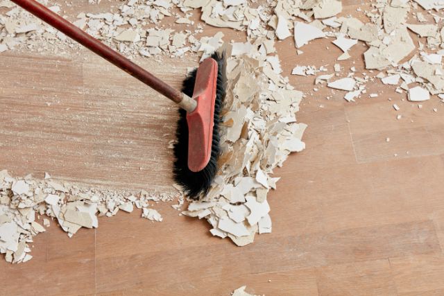 A contractor cleaning the area after peeling the old paint from walls.