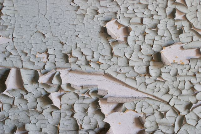 Paint peeling on an exterior concrete wall.