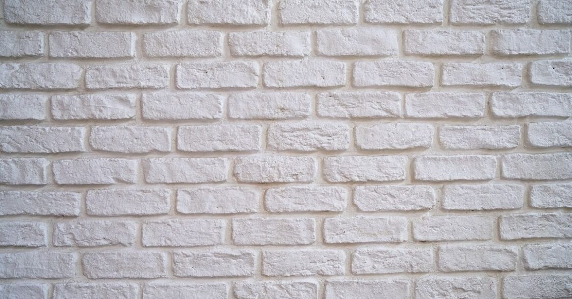 White painted brick wall with textured surface, ideal for modern interior or exterior design backgrounds.