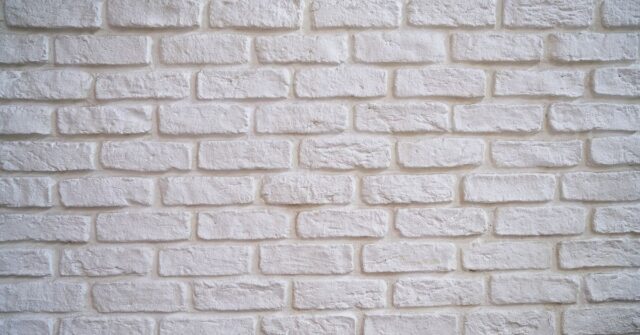 White painted brick wall with textured surface, ideal for modern interior or exterior design backgrounds.