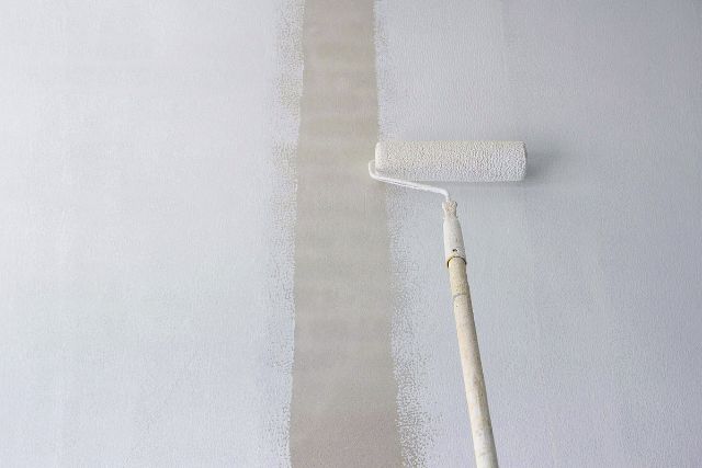 Paint primer applied using a long handled roller brush.