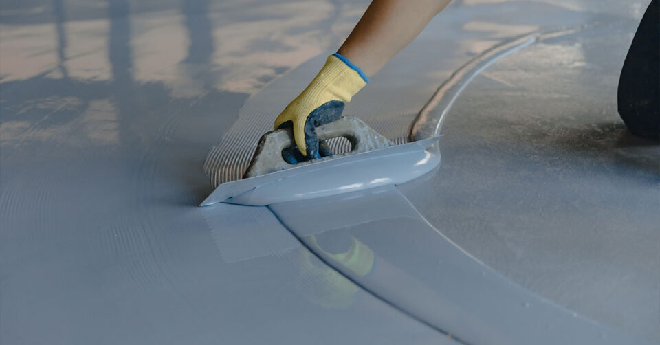 Epoxy floor coating being applied and smoothed out by hand.